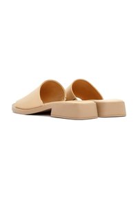 Mules beiges à enfiler avec un dos ouvert, en simili cuir lisse, talon carré et semelle plate, présentant un design minimaliste et sans motifs.