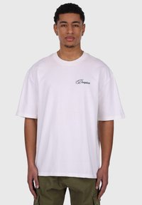 White cotton t-shirt with a round neckline and short sleeves. Features a black embroidered logo on the left chest. Casual fit.