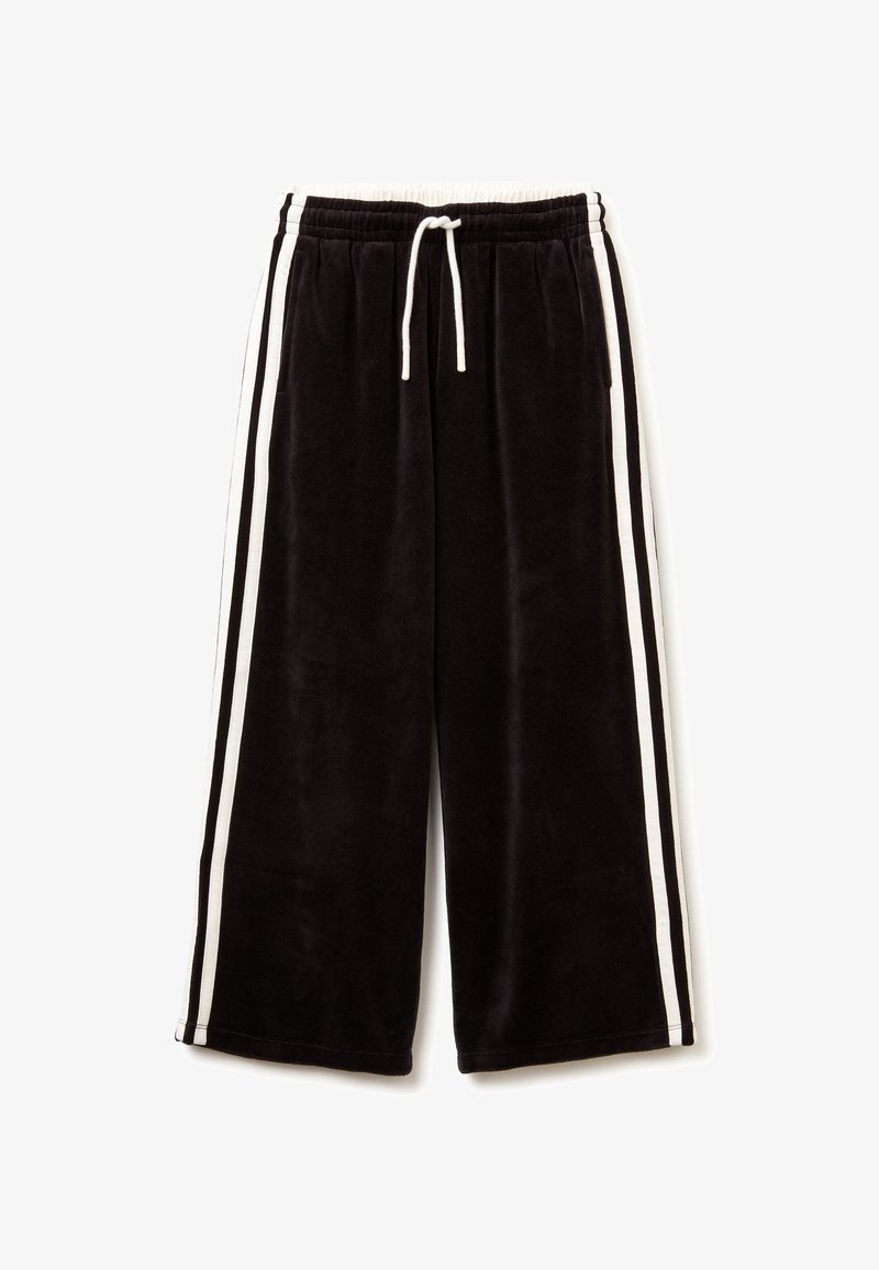 Černé velurové tepláky s bílými postranními pruhy, elastickým pasem a nastavovacími šňůrkami. Mají volný, zkrácený střih.