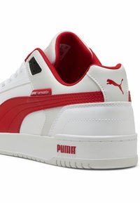 Weißer Sneaker mit rotem Seitenstreifen, Obermaterial aus synthetischem Leder, strukturierte rote Akzente an der Ferse und rotem "PUMA"-Logo an der Ferse.