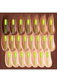 Rangées de 24 tubes de correcteur avec des bouchons vert néon présentés sur des échantillons correspondants allant des teintes de peau foncées aux teintes claires.