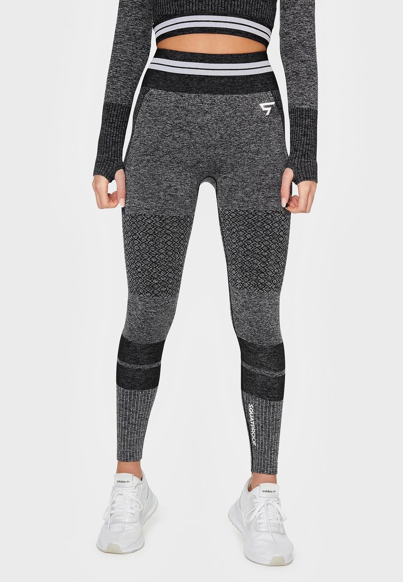Šedé fitness legíny s texturovanými vzory, různými odstíny a vysokým pasem. Obsahují žebrované akcenty a detail loga na lýtku.