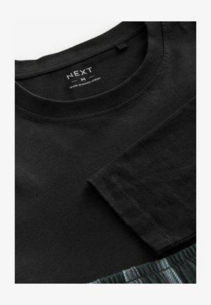 Svart bomullströja med rund hals och korta ärmar. Har en slät yta och en etikett med märket "NEXT" och storlek "M".