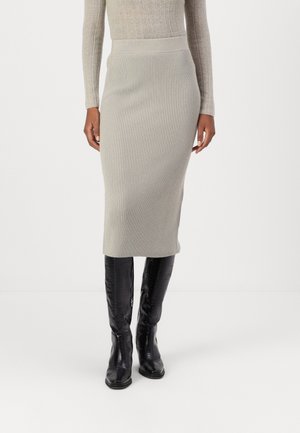 Knit, mid-length skirt in light gray with ribbed texture and a fitted waistband. Paired with knee-high, glossy black boots.