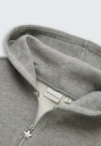 Grijze hoodie met een rits, met een lichte glans, fleece interieur en een stervormige trekker. Etiket zegt "TOM TAILOR."
