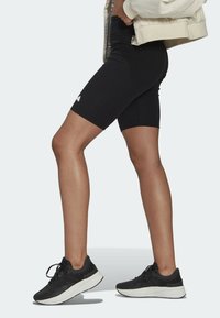 Svarta ribbade cykelbyxor med en åtsittande design, ihop med svarta sneakers med en vit sula. Nyckeldetalj: liten logotyp på byxorna.