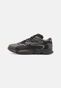 Black athletic shoe featuring a textured upper with grey accents, a cushioned sole, and round toe design. Laces and branding detail visible.