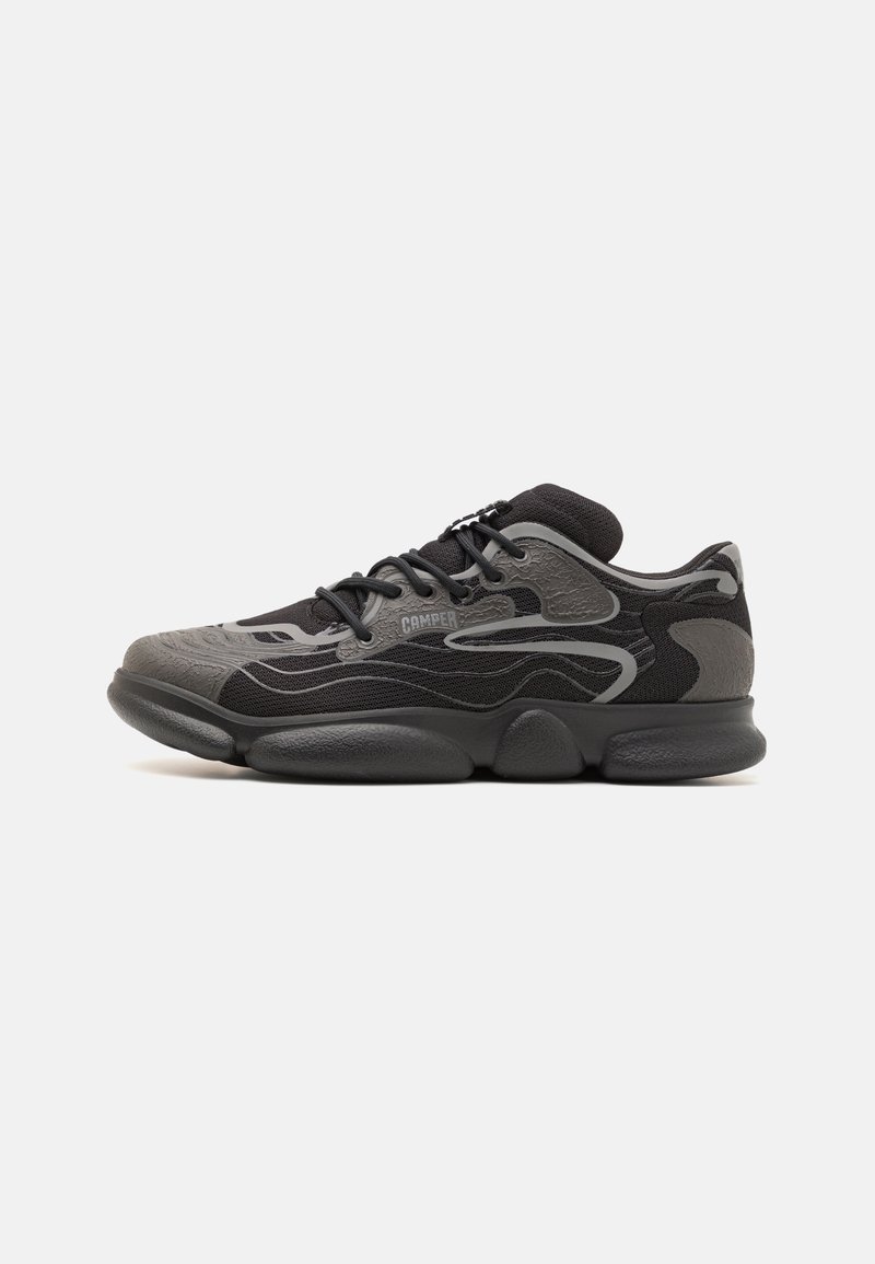 Black athletic shoe featuring a textured upper with grey accents, a cushioned sole, and round toe design. Laces and branding detail visible.