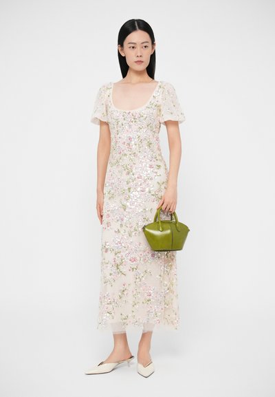 Kvetinové šatky s flitrami v svetloružovej farbe s krátkymi nadýchanými rukávmi, doplnené malou zelenou kabelkou a bielymi špicatými balerínami.