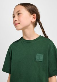 Grøn bomulds t-shirt med en tekstureret, gummieret logo-patch. Rund hals, korte ærmer og en afslappet pasform. Simpelt design uden mønstre.