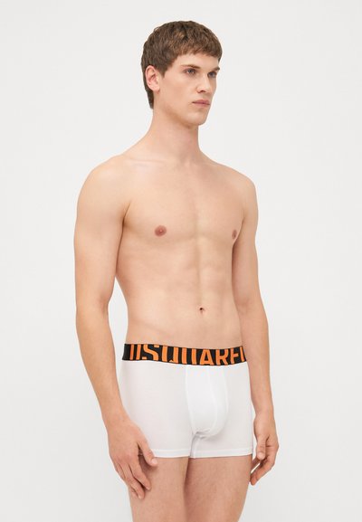 White boxer briefs with a black waistband featuring bold orange lettering. The fabric has a smooth texture and a fitted design.