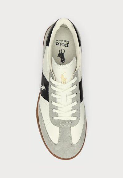 Valged ja hallid sneakerid mustade aktsentidega, tekstuuriga samet ja nahk, lapikud paelad, kummist tald ja logo detail keeles.