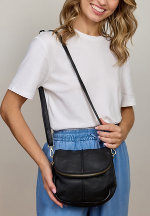 Borsa a tracolla nera in pelle con chiusura a zip, forma curva e tracolla regolabile, caratterizzata da accessori in metallo dorato e superficie testurizzata.