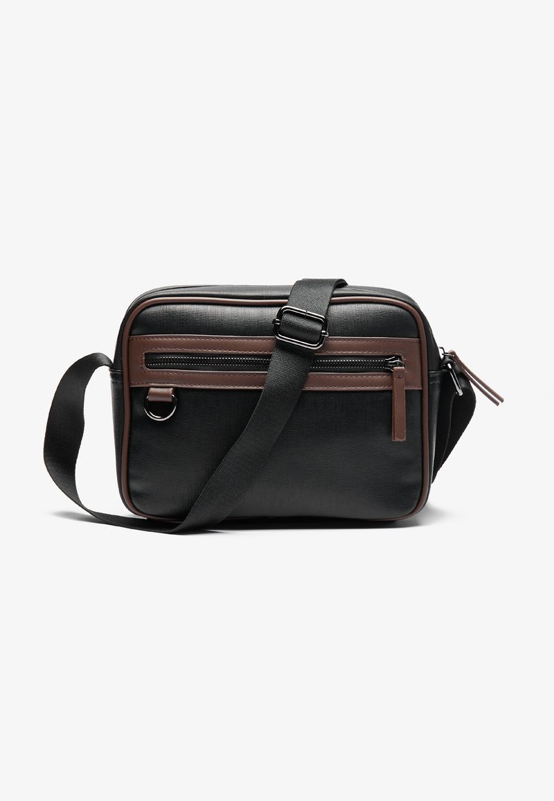 Sac messager noir en tissu texturé, avec un accent en cuir marron, une bandoulière réglable et une poche avant zippée.