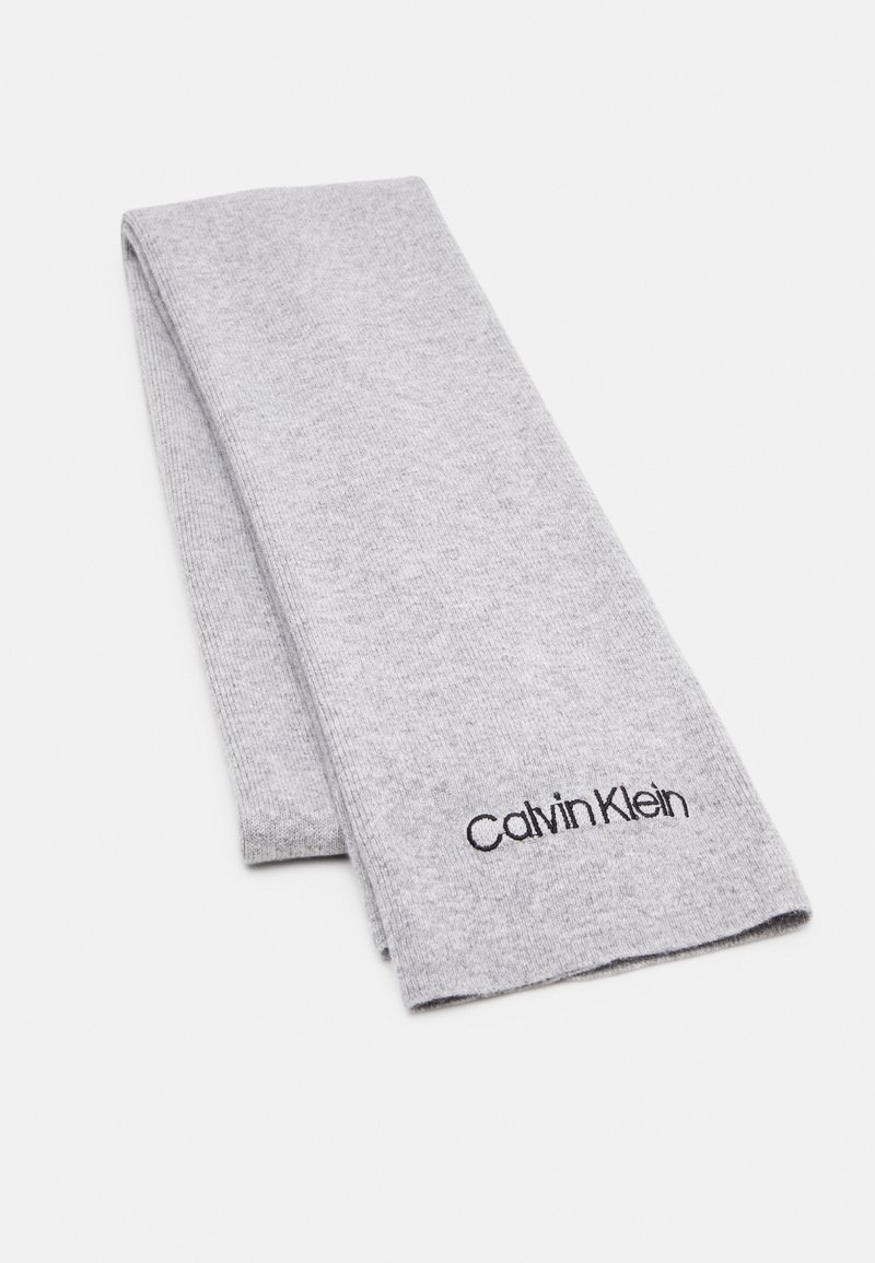 Écharpe pliée en tricot gris clair avec logo "Calvin Klein" noir brodé près d'une extrémité sur un fond blanc.