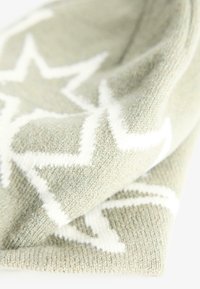 Eșarfa tricotată de culoare verde deschis, cu un model de stele în alb. Materialul are o textură moale și un aspect confortabil.