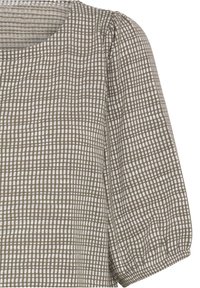 Gros plan d’un haut en tissu à carreaux beige et blanc avec un col rond et des manches trois-quarts bouffantes.