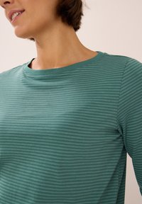 Teal striped long-sleeve shirt with a round neckline. The fabric appears soft and textured with a subtle sheen and a classic fit.