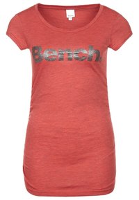 Rød kortærmet t-shirt med rund halsudskæring, prydet med et stort sølvglitrende logo "Bench." foran. Blødt, struktureret stof.