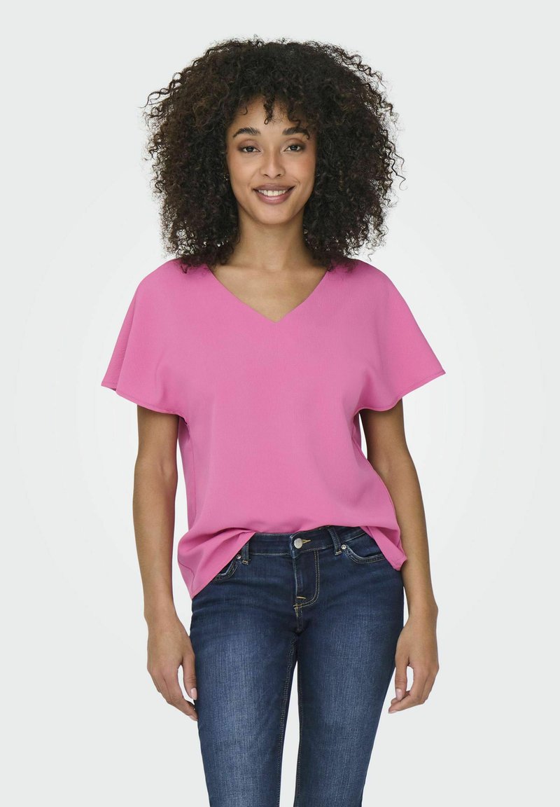 Lys rosa, kortærmet bluse med V-halsdesign, lavet af letvægtsstof. Båret med mørkeblå jeans. Enkle, klare linjer og afslappet pasform.