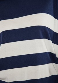 Țesătură tricotată în dungi albastre închise și albe, cu linii orizontale îndrăznețe. Textura este netedă și moale, concepută pentru confort.