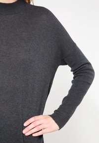 Maglione grigio a maglia con collo alto e maniche lunghe. Caratterizzato da una vestibilità comoda e una texture morbida, adatto all'uso casual.