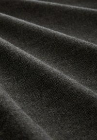 Tmavě šedá tkanina s měkkým, strukturovaným povrchem, která obsahuje jemné tkané vzory a jemné záhyby vytvářející strukturovaný vzhled.