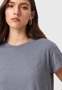 Camiseta gris de manga corta con cuello redondo, hecha de algodón suave. Presenta un ajuste relajado y una textura lisa sin ningún patrón.