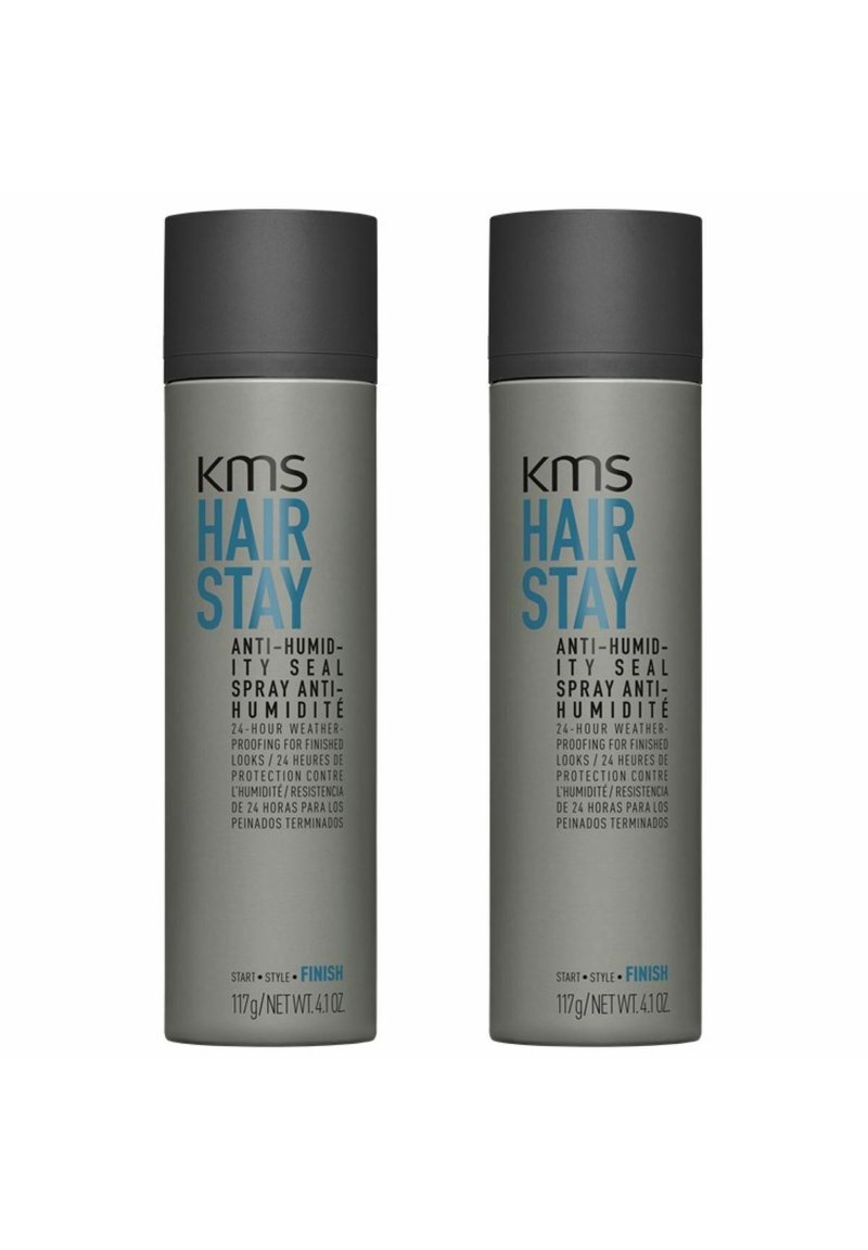 Zwei graue Sprühdosen mit der Aufschrift "KMS Hair Stay Anti-Humidity Seal." Jede 117 g, mit einem dunklen Deckel und blauen Texten, die die Produkteigenschaften beschreiben.