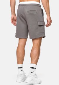 Pantalones cortos de mezcla de algodón gris con una cintura elástica, bolsillos traseros y un bolsillo de carga lateral; acabados con una textura suave y detalles cosidos.
