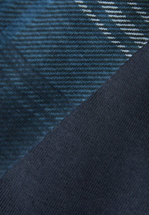 Modrý textil s dvoma časťami: jedna časť s diagonálnymi pruhmi a rôznymi odtieňmi modrej, druhá časť má jednoliatu tmavomodrú farbu s textúrovaným povrchom.