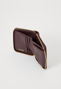 Burgundy leather wallet with gold zipper, multiple card slots, and a smooth texture; features embossed logo on the interior.