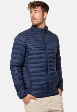 Marineblå pufferjakke med vandret quilted tekstur, høj krave og lynlås. Materialet fremstår let og vandafvisende.