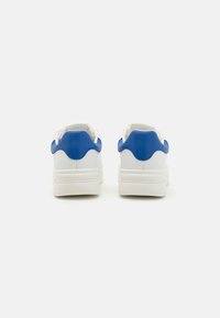 Hvite sneakers med blå detaljer, med en glatt skinnoverdel, polstret krage og teksturerte gummisåler med en lett hæl.