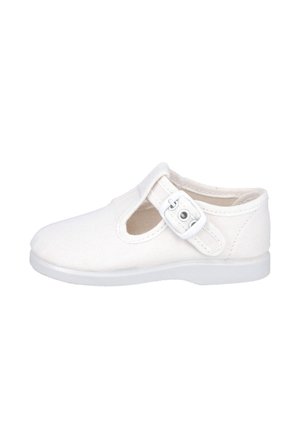 Zapato infantil blanco de lona con una sola correa con hebilla y una abertura en el lateral, con una suela de goma plana.