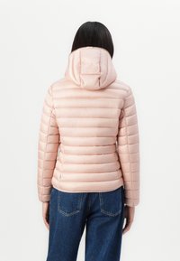Lys rosa pufferjakke med horisontal søm, hette og figursydd silhuett, kombinert med mørkeblå høytlivsjeans.