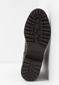 Semelle de botte marron avec un motif de bande de roulement profond pour une meilleure traction. Comprend un caoutchouc texturé, un design robuste et une étiquette du fabricant embossée.