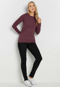 Pitkähihainen, viininpunainen ja tumma vaaleanpunainen raidallinen paita, pari mustien skinny-farkkujen ja valkoisten lenkkarien kanssa, jossa on tiukka malli ja pyöreä kaula-aukko.