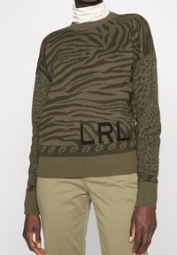 Maglione verde oliva con motivi di tigri e leopardi, con polsini e orlo a costine, e un logo "LRL" nero sul davanti.