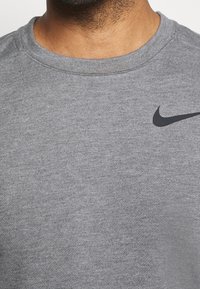 Grijze sweatshirt van een katoenmix, met een ronde hals en een zwart Nike-logo op de bovenkant links. Zachte textuur.