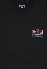 Black Billabong T-shirt with a small colorful tropical design, including a sun and palm trees, printed on the upper left chest.
