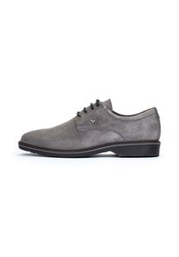 Chaussure habillée en suède gris avec une texture lisse, bout rond et semelle plate en caoutchouc noir. Présente cinq œillets et un accent de logo subtil.