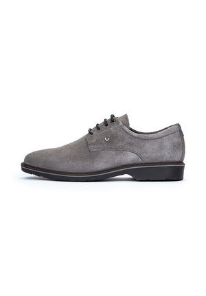 Chaussure habillée en suède gris avec une texture lisse, bout rond et semelle plate en caoutchouc noir. Présente cinq œillets et un accent de logo subtil.