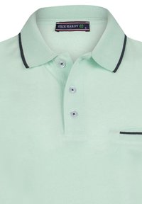 Polo de color verde menta claro con tejido texturizado, cuello con ribetes en azul marino, tres botones y un pequeño bolsillo en el pecho con borde contrastante.