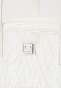 Borsa tote bianca con una finitura lucida, caratterizzata da un motivo geometrico. Include una placca logo argentata e manici robusti.