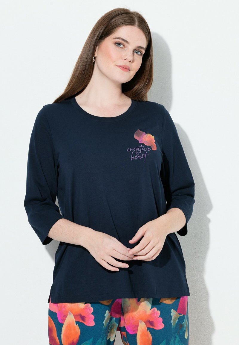 Marineblaues Oberteil mit dreiviertellangen Ärmeln, verziert mit einer bunten Blumen-Grafik und dem Text "kreatives Herz". Weiches Baumwollmaterial.