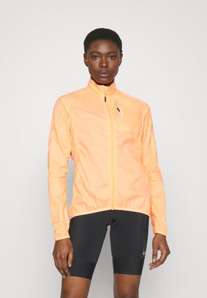 Leichte, leuchtend orange Freizeitjacke mit Reißverschluss, hohem Kragen und elastischen Bündchen, kombiniert mit schwarzen Radshorts.
