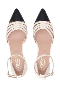 Beige Riemchenhigh Heels mit schwarzer spitzer Schuhspitze. Sie verfügen über ein Slingback-Design mit einem Knöchelriemen und einer strukturierten Innensohle. Goldene Markenkennzeichnung sichtbar.