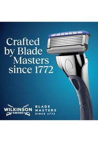 Miesten partahöylä, jossa useita teriä ja siniset yksityiskohdat, vieressä teksti "käsityötaitoa vuodesta 1772" ja Wilkinson Sword -brändäys.