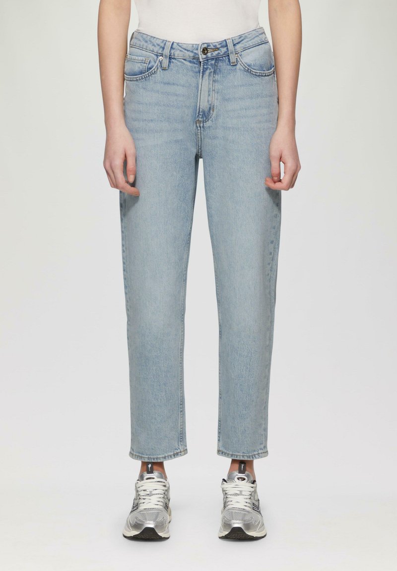 Jasnoniebieskie dżinsy z prostym krojem nogawek, wysokim stanem, pięcioma kieszeniami i subtelnym przetarciem. W połączeniu z srebrnymi butami sportowymi.